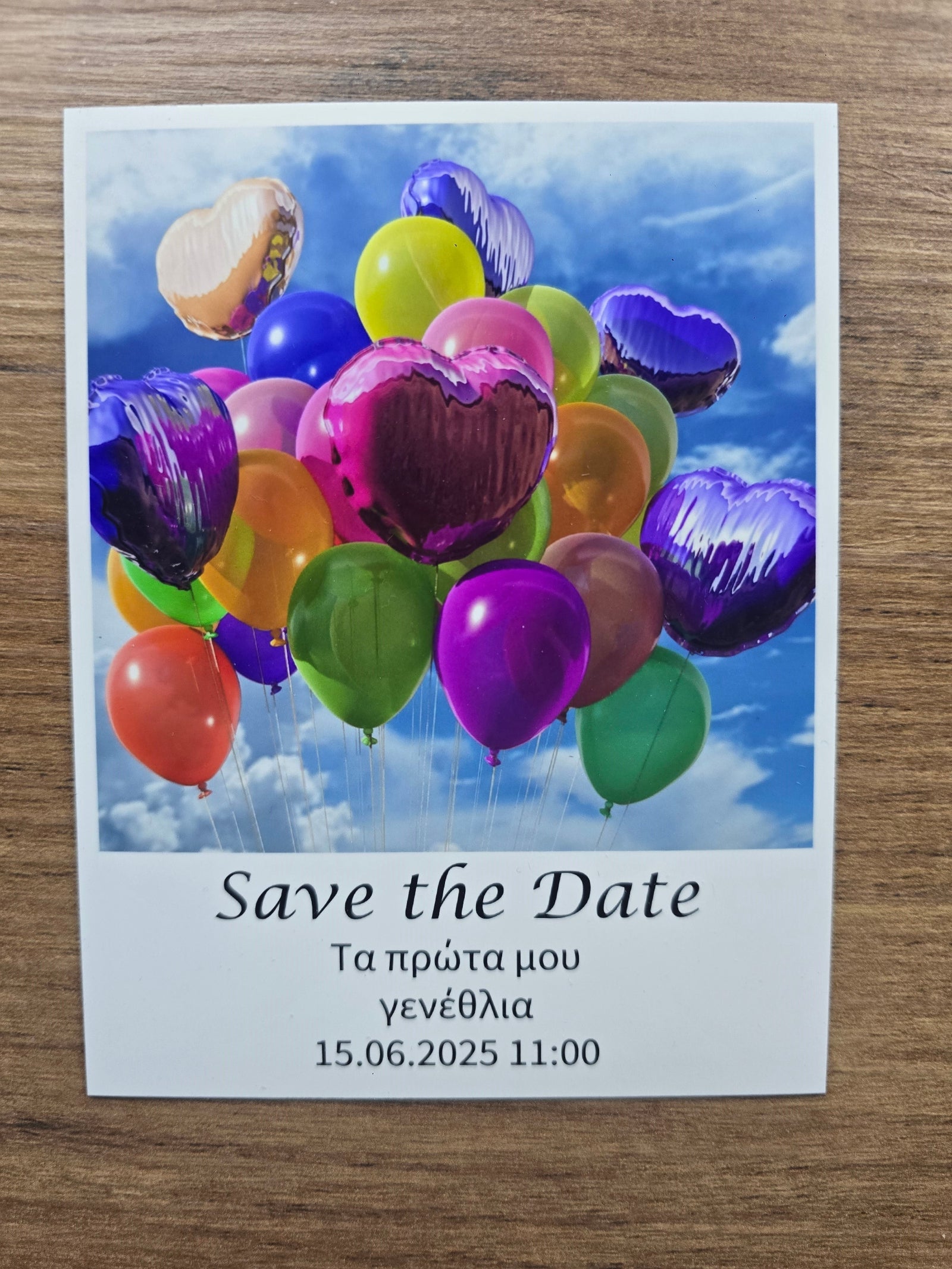 Save the Date photo magnet with colorful balloons and a sky background on a wooden surface.