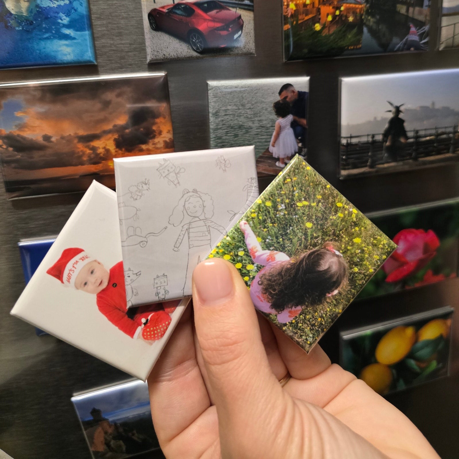 Collection of photo magnets on a wall with a hand holding a photo magnet.