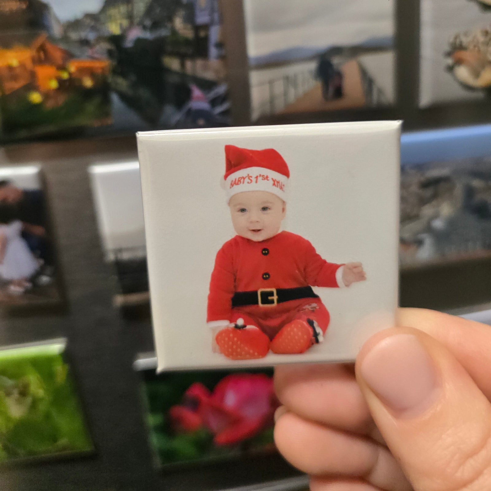 Photo magnet with a child in a Santa outfit held in front of a collection of photo magnets.