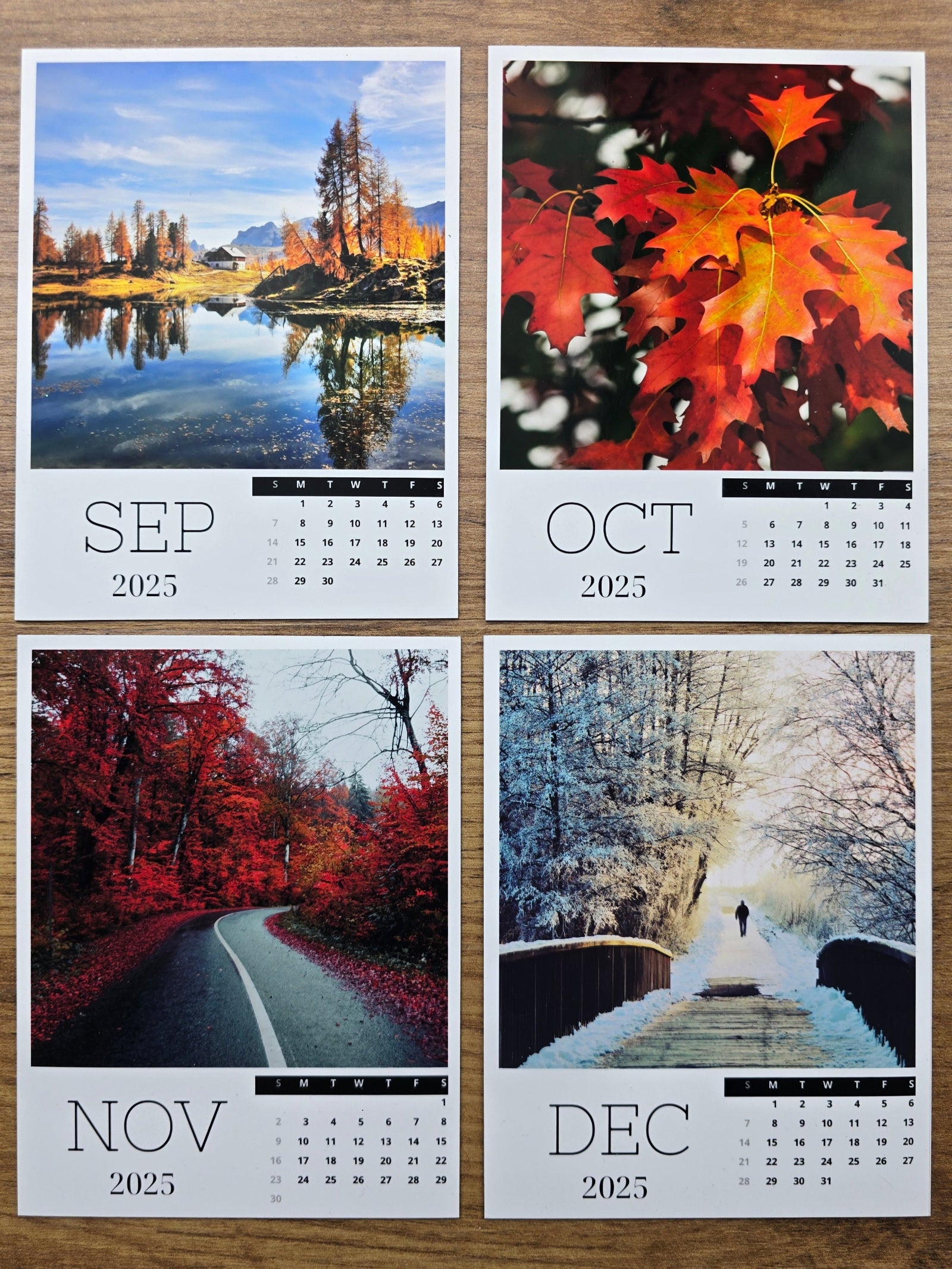 Four photo magnet calendar pages showing autumn and winter scenery on a wooden surface.