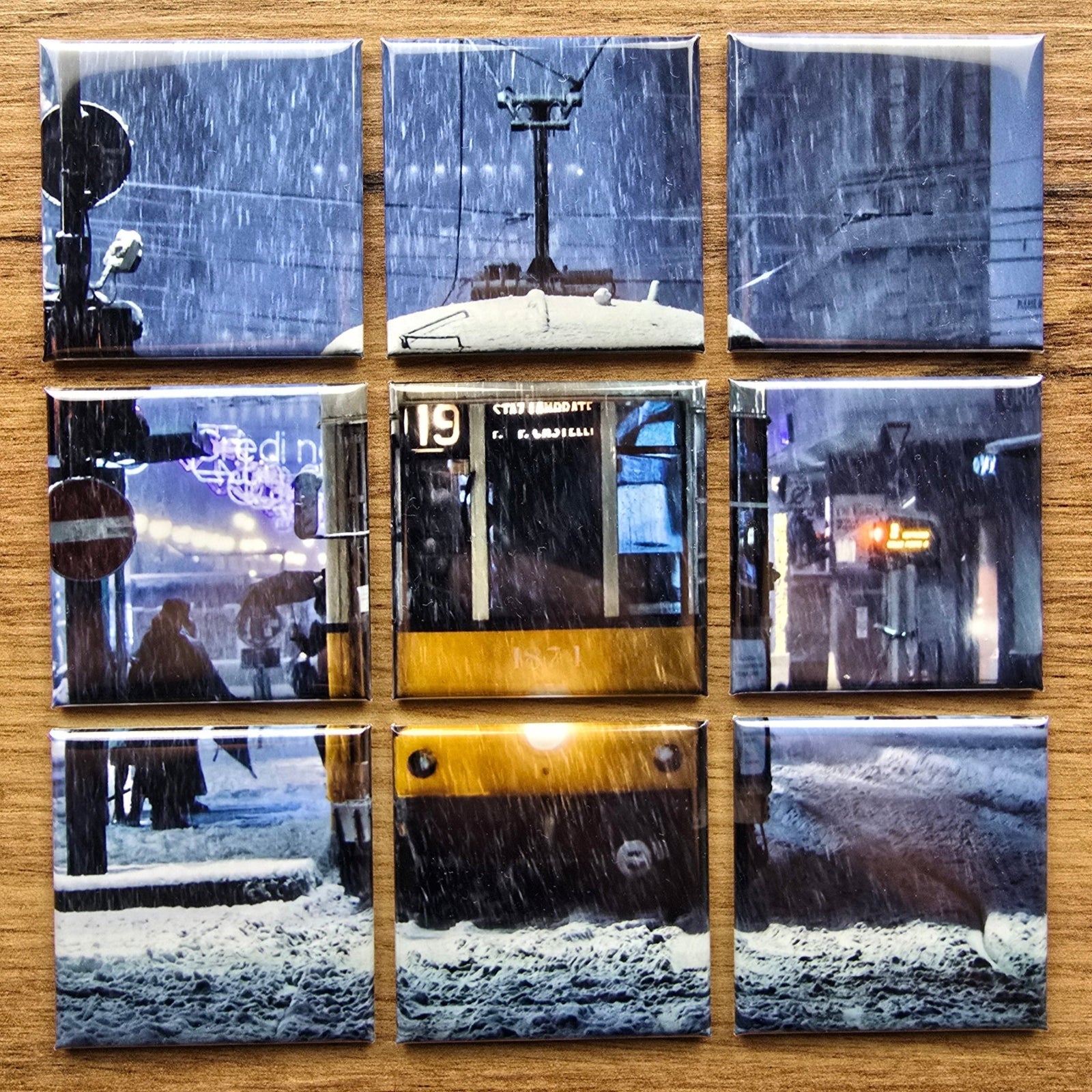 Nine square photo magnets arranged in a grid on a wooden surface.