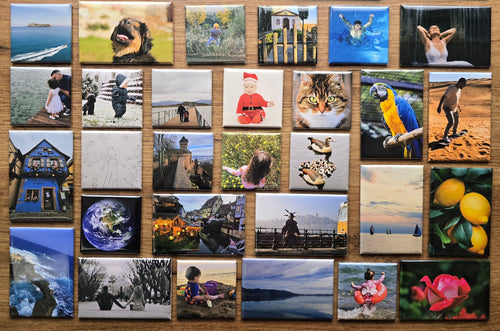 Collection of photo magnets arranged in a grid on a wooden surface.